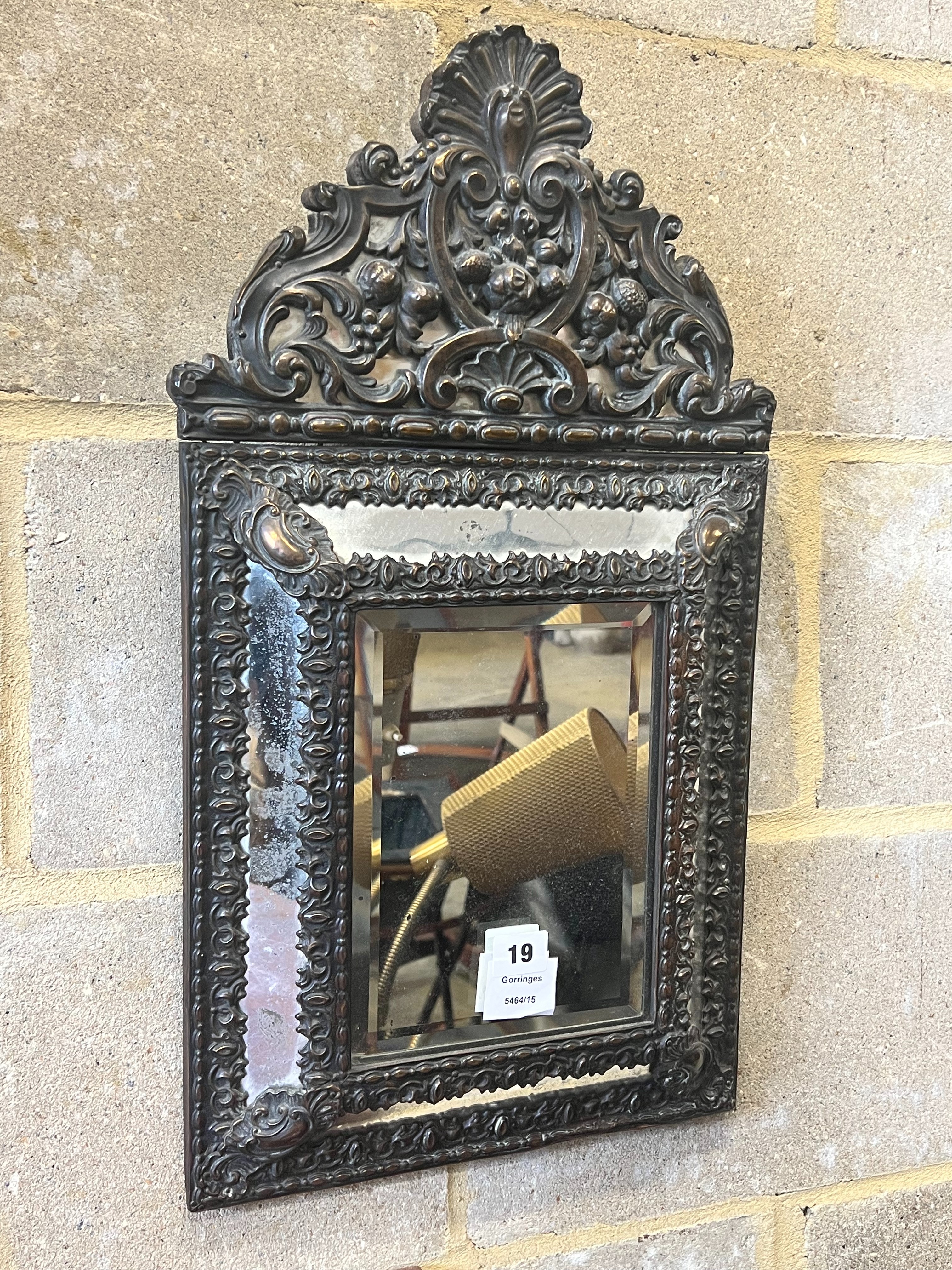 A Dutch brass framed cushion wall mirror, with ornate arched cresting, pierced and repousse with birds, scrollwork and shell surmount, width 33cm height 58cm
